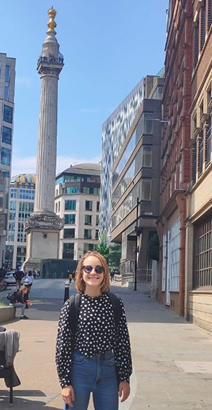 Image of Julia Sisk-Reynés standing on an urban street in front of a monument.