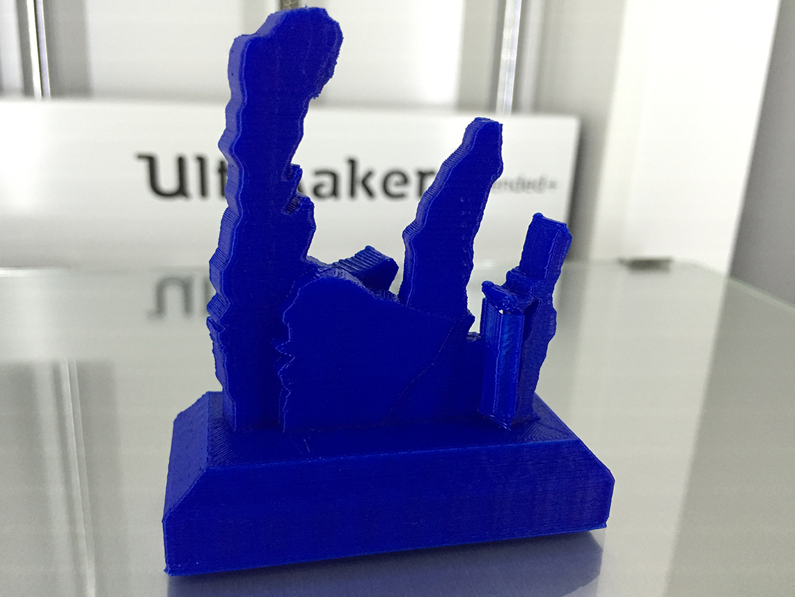 Photo of a 3D print of M16, the Eagle Nebula. The print is about 5 inches tall, built using blue plastic. There are three vertical columns staggered, rising up like fingers extending from the palm of a hand.